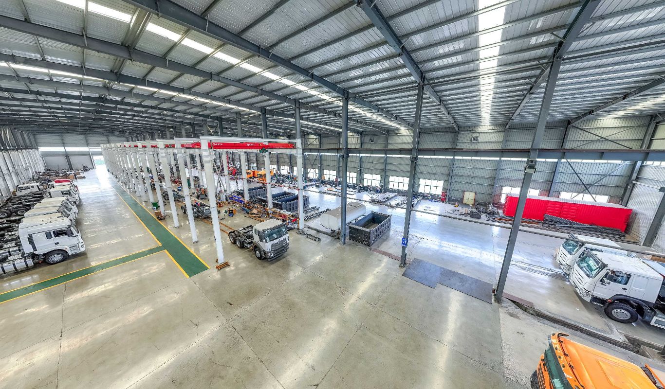 Inside our workshop: rows of new HOWO tractor units, chassis and dump bodies under overhead cranes