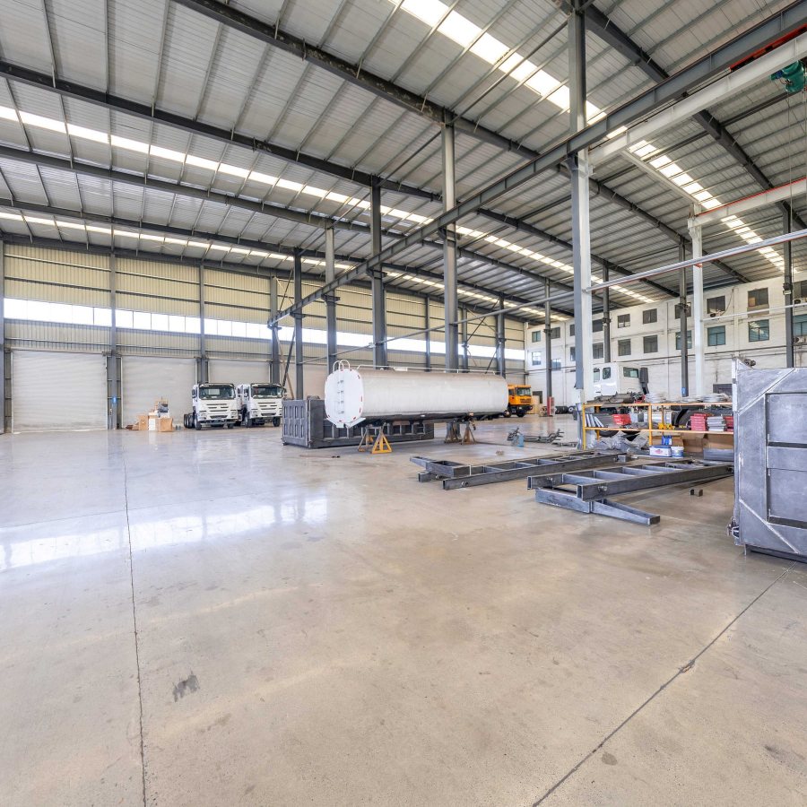 Fabrication workshop with dump bodies and a truck under an overhead crane